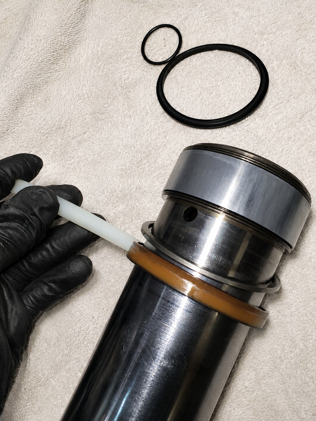 Gloved hand seating a seal onto a polished hydraulic shaft during precision repair